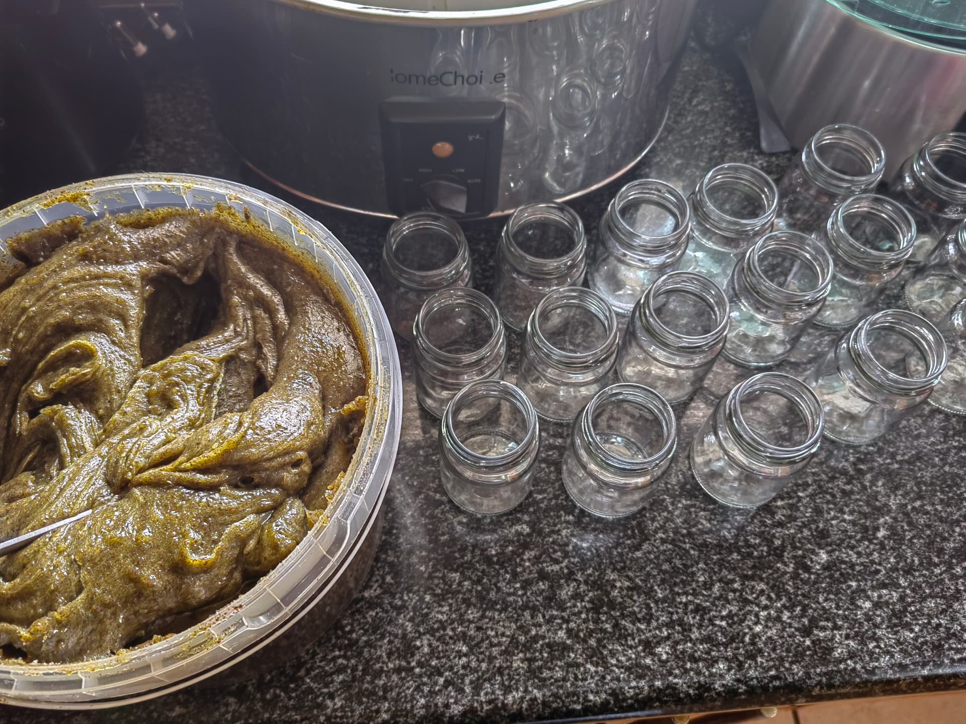 A batch of Sanyu Hair Growth Balm in the mixing bowl, beside empty jars